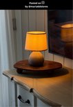 Petite lampe de table avec base ronde grise et abat-jour orange sur un plateau en bois.