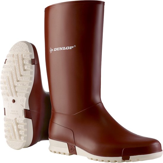 Botte marron Dunlop avec semelle et côté blancs, et une semelle détachée à côté.