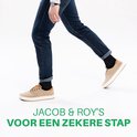 Man in spijkerbroek en sneakers draagt zwarte sokken van Jacob & Roy's.