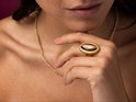 Gouden ring met ovaal, bruin gestreept tijgeroog in een verhoogde zetting. De ring is gedragen door een model.