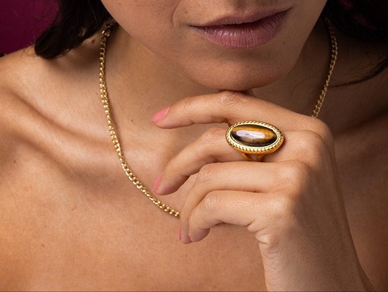 Gouden ring met ovaal, bruin gestreept tijgeroog in een verhoogde zetting. De ring is gedragen door een model.