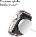 Een smartwatch met sterrenlichtkleurige beschermhoes wordt draadloos opgeladen op een lader.