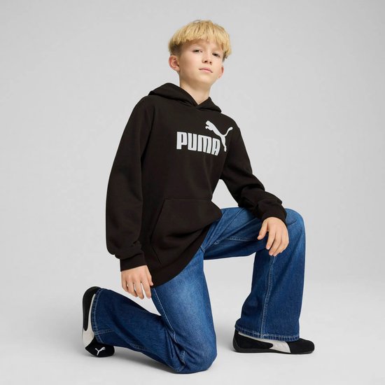 Jongen knielt in een zwarte PUMA hoodie en spijkerbroek, met logo op de borst.