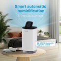 Witte luchtreiniger op een houten tafel in een slaapkamer, met de tekst 'Smart automatic humidification'.