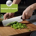Un chef coupe des légumes avec un couteau de chef à motif damassé et manche noir. "Durable et inoxydable"