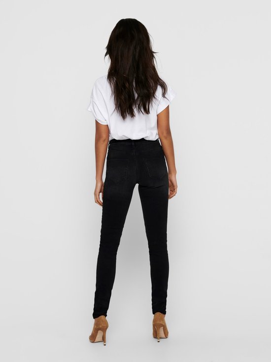 Model van achteren gezien in een strakke zwarte spijkerbroek met hoge taille.