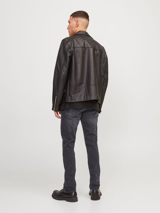 Man in zwarte bikerjack en grijze jeans, gezien vanaf de achterkant.
