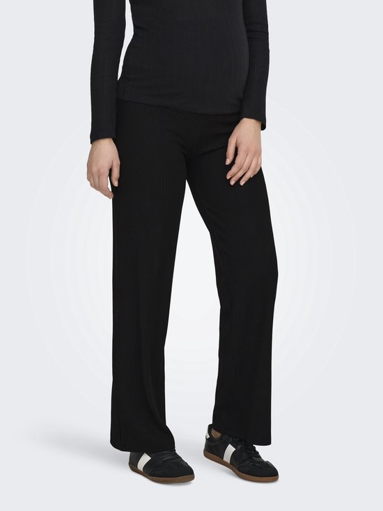 Model van voren met een zwarte nauwsluitende top en een zwarte wijde ribbroek.
