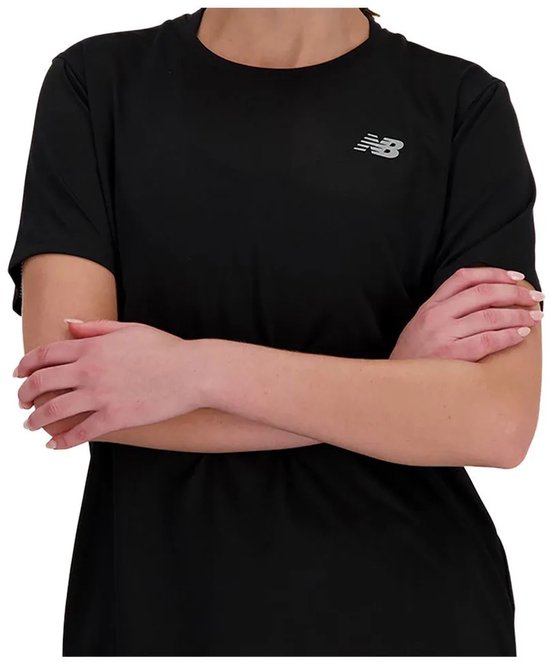 Zwart sportshirt van New Balance met logo op de borst, armen gekruist gedragen door een model.