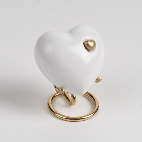 Wit hartvormig urn met gouden hartdetail en gouden standaard.