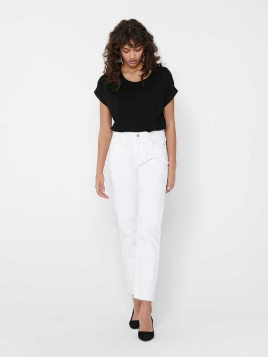 Model in zwart T-shirt met opgerolde mouwen en witte jeans met rafels.