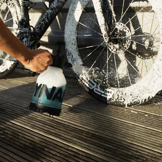 Een hand spuit een fietswiel in met schuim uit een spuitfles.
