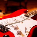 Close-up van een rode elektrische gitaar, met de tremolo-arm op de witte slagplaat.