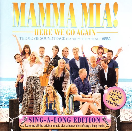 De cast van Mamma Mia! Here We Go Again staat op een houten pier, met de oceaan op de achtergrond. Het artwork heeft de tekst 'Sing-A-Long Edition'.