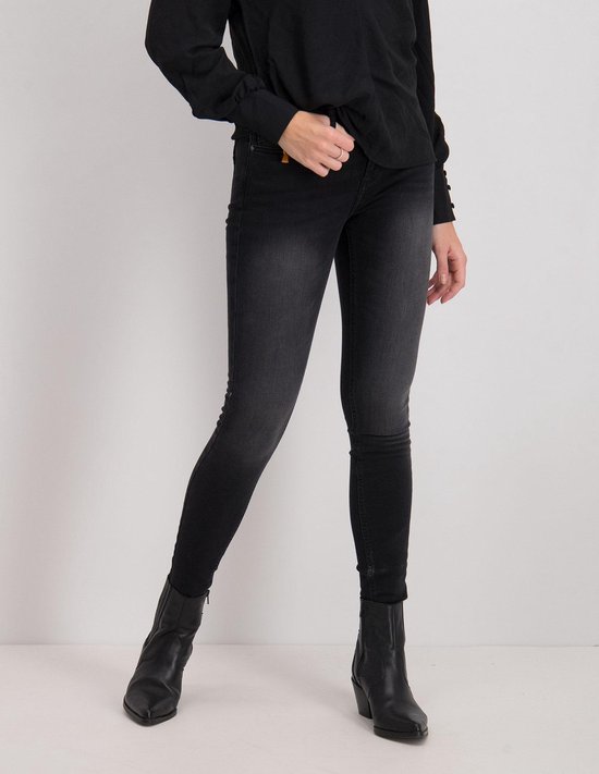 Model in zwarte skinny jeans en zwarte laarsjes.