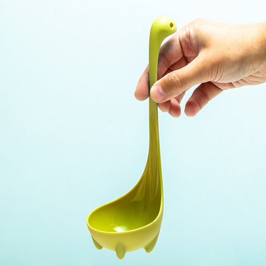 Hand houdt een groene Nessie soeplepel omhoog, met de soeplepel leeg.