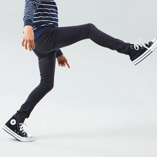Jongens model in een skinny jeans en een gestreepte longsleeve.