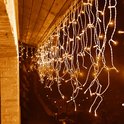 Sfeervolle warm witte ijspegelverlichting langs de rand van een dakoverstek in het donker.