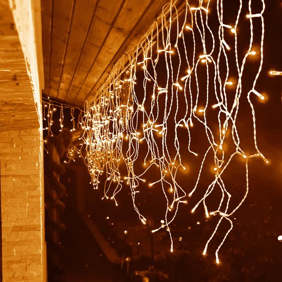 Sfeervolle warm witte ijspegelverlichting langs de rand van een dakoverstek in het donker.