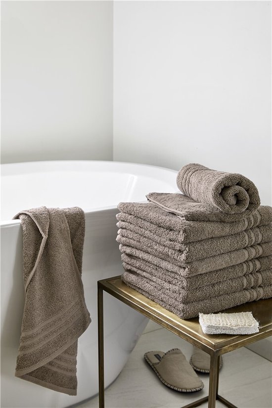 Serviettes taupe dans une salle de bain près d'une baignoire et sur une table d'appoint.