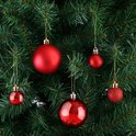 Vijf rode kerstballen van verschillende maten hangen aan een kerstboom.