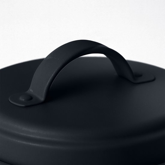 Close-up van het donkergrijze metalen deksel van een voorraadpot met een gebogen handvat.