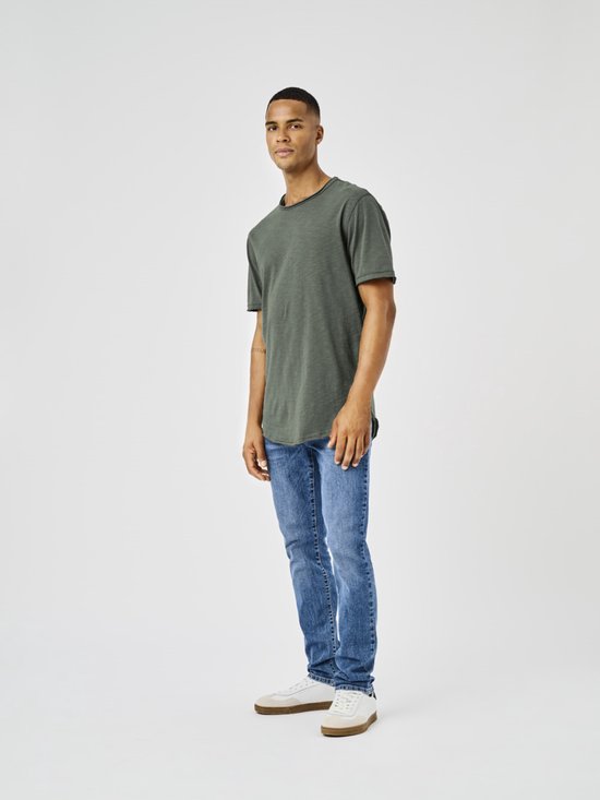 Man in groen T-shirt en blauwe jeans,posed opzij.
