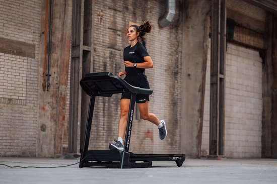 Vrouw rent op zwarte Focus Fitness Jet 4 loopband, profiel van links.