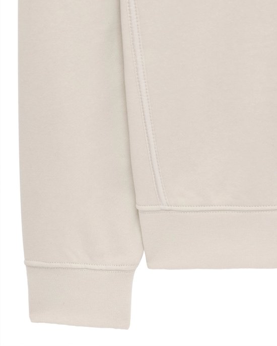 Detail van de mouw en boord van een beige trui.