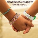 Twee handen houden elkaar vast, met aan elke pols een handgemaakte paracord armband met infinity symbool en een knoop
