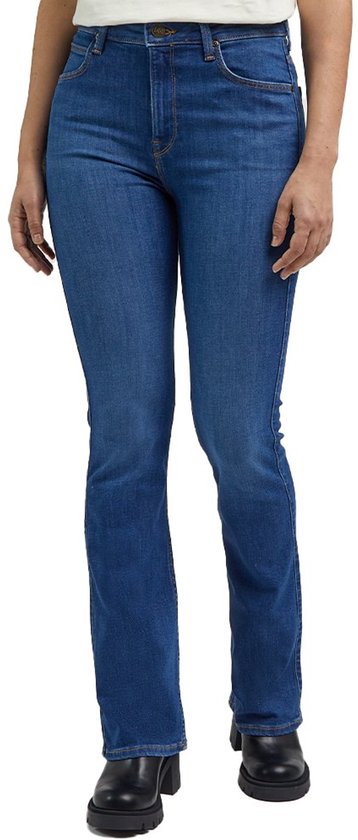 Vrouw, staand op de voorkant, draagt een blauwe spijkerbroek met een bootcut pasvorm en een licht uitlopende pijp.