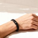 Zwarte gevlochten lederen armband met kralen van zwarte lavasteen en mat zwart, gedragen om een mannenpols.