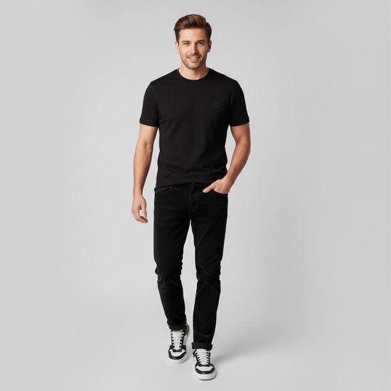 Man met zwarte corduroy broek en zwart T-shirt, lachend, loopend.