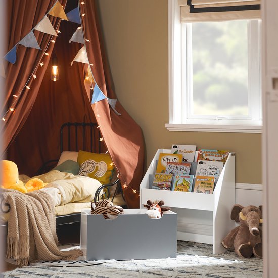 Kinderkamer met een bed, boekenrek en speelgoedkist, versierd met slingers.