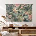 Een tropische bladerenprint in groen en roze op een wandkleed, hangend boven een houten dressoir met een stoel.