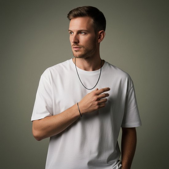 Man met witte T-shirt draagt een zwarte ketting en armband met kleine vierkante schakels.