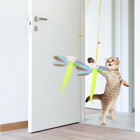 Een cyperse kat springt naar een felgroen, libelle-vormig kattenspeeltje dat aan een koord boven een deuropening hangt.