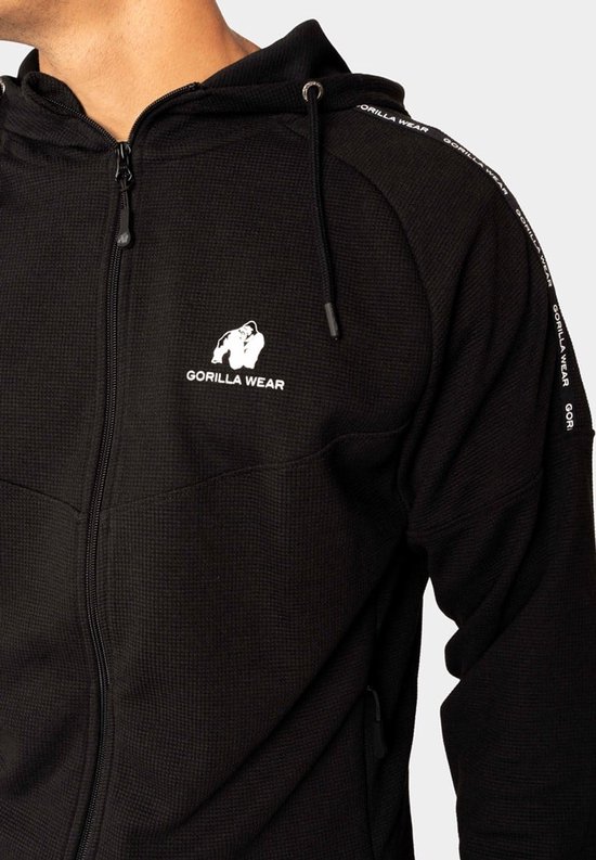 Detail van een zwarte trainingsjas met rits, capuchon en het logo van Gorilla Wear op de borst.