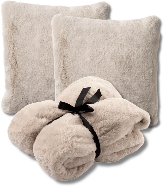 Twee beige sierkussens en een opgerolde beige plaid, vastgebonden met een zwarte strik.