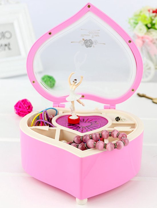 Roze hartvormig muziekdoosje met gouden rand. Ballerina in witte tutu danst op een roze platform. Sieraden zichtbaar.