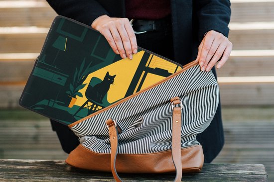 Donkergroene laptophoes met zwart kat-motief, wordt in een tas gestopt.