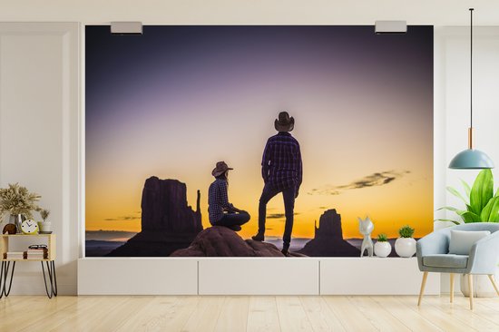 Deux cowboys dans une zone de montagne au coucher du soleil fotobehang