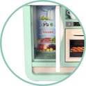 Mintgroene speelgoedkoelkast met open deur, gevuld met speelgoedfruit, groenten, eieren en flessen melk. De oven ernaast bevat speelgoedkoekjes.