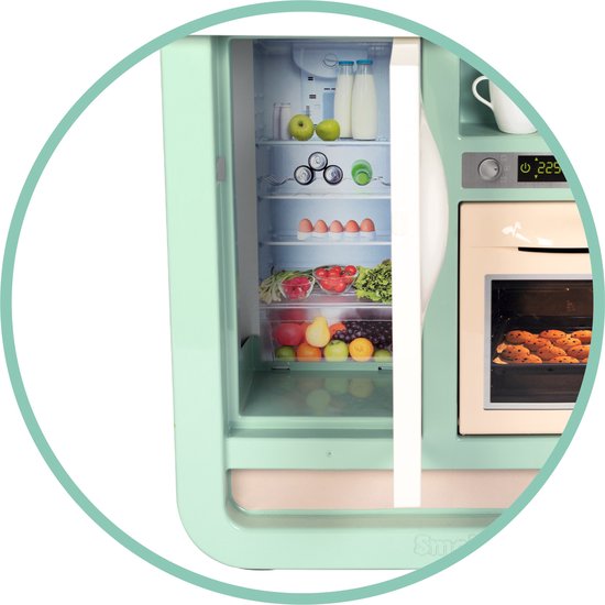 Mintgroene speelgoedkoelkast met open deur, gevuld met speelgoedfruit, groenten, eieren en flessen melk. De oven ernaast bevat speelgoedkoekjes.