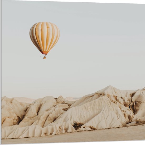 Dibond - Oranje met Wit Gestreepte Luchtballon Vliegend boven Beige Rotsen - 80x80 cm Foto op Aluminium (Met Ophangsysteem)