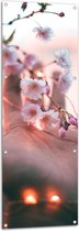 Tuinposter – Hand bij Roze Bloemen met Lichtjes - 50x150 cm Foto op Tuinposter (wanddecoratie voor buiten en binnen)
