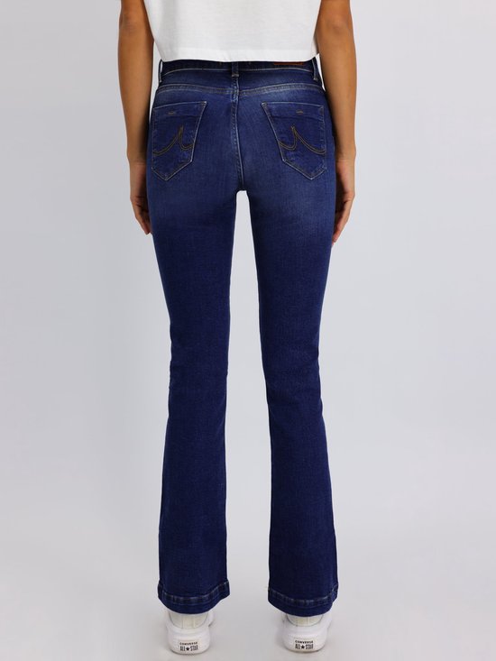 Achterkant van een vrouw in een donkerblauwe flared jeans met een brede zoom en stiksels.