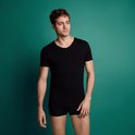 Man met een zwarte t-shirt met v-hals en korte mouwen, staand.