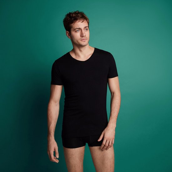 Man met een zwarte t-shirt met v-hals en korte mouwen, staand.
