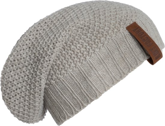 Lichtgrijze gebreide muts met een leren label met 'Knit Factory' erop.